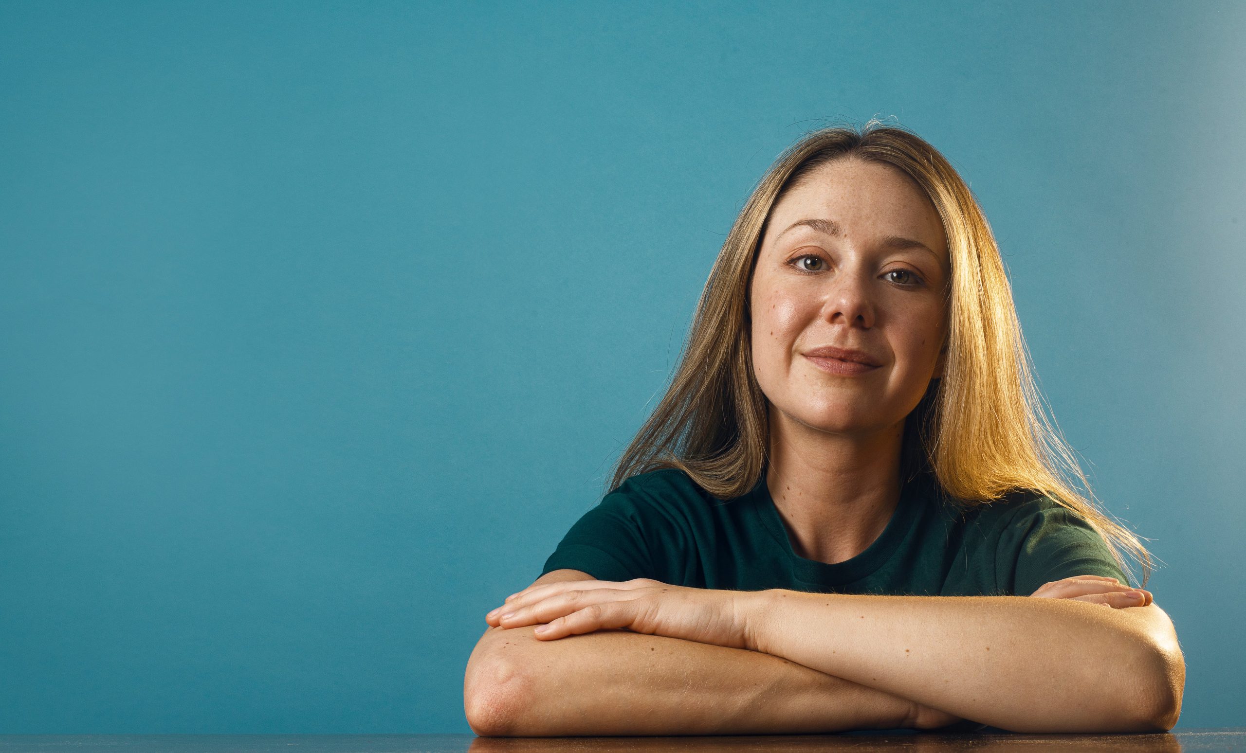a woman in a plain green shirt against a blue backdrop